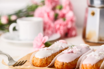 Traditional french eclairs on white table with pink flower. Copyspace