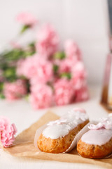 Traditional french eclairs on white table with pink flower. Copyspace