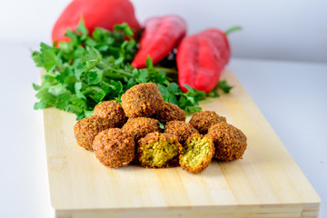 Falafel balls,sweet red pepper and green fresh parsley on a wooden background.Falafel is a traditional Middle Eastern food.