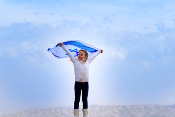 Little patriot jewish girl standing  and enjoying with the flag of Israel on blue sky...