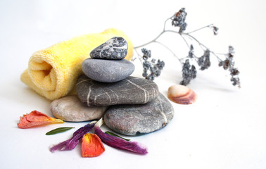 .gemstone stones on each other, flower petals, yellow rolled towel and a dry branch of a field...