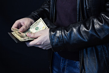 A man counts money in a purse, theft, a black background