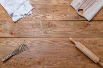 Old wooden rustic table with various kitchen utensils, rolling pin, napkin, wooden deck, syringe for cream, spoon, top view, copy space