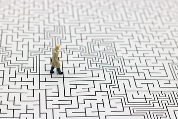 Miniature people: Businessman standing on center of maze. Concepts of finding a solution, problem solving and challenge.