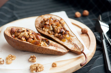 Dessert from the baked pears with honey and nuts in a wooden plate