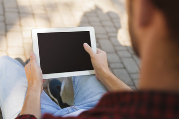 Male hands with tablet closeup,over shoulder shot outdoors