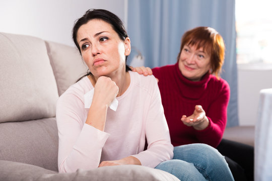 Unhappy women sitting at sofa after conflict at home