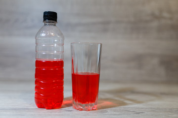 Sports set, energy drink in glass and plastic bottle on wooden table, pill box. Energy for workout in a gym.