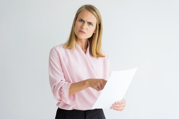 Disgruntled lady boss dissatisfied with report and pointing at mistake in paper. Annoyed...