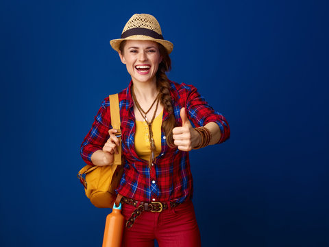 smiling traveller woman on blue background showing thumbs up