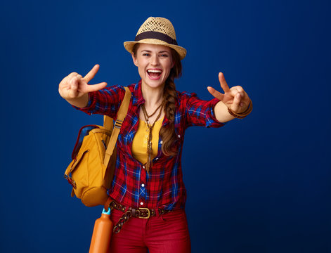 happy traveller woman on blue background showing victory