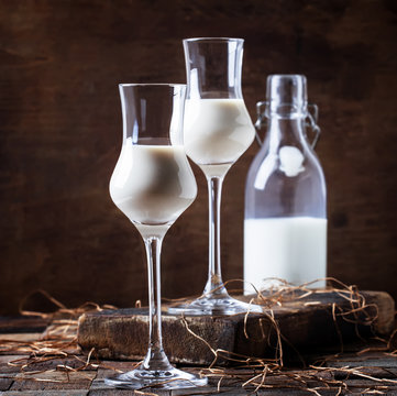 Creamy liqueur in shot glasses, rustic style, vintage wooden background, selective focus