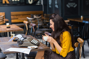 Female writer with vintage typewriter in a coffee shop