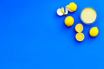 Lemon curd in bowl among lemons on blue background top view copy space