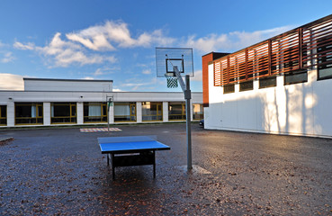 Outdoor school playground in the school courtyard with a basketball basket and table tennis table....
