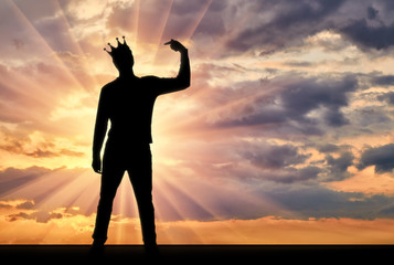 A silhouette of a narcissistic man with a crown on his head shows his finger on himself. He tries...