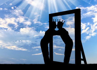 Silhouette of a narcissistic man with a crown on his head hugging his reflection in the mirror