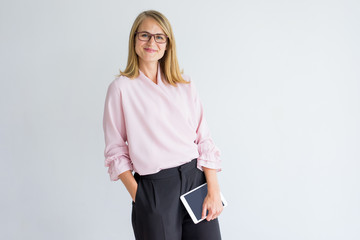 Smiling modern business lady with tablet wearing stylish clothes and eyeglasses looking at camera. Confident woman succeed in career. Modern lady concept