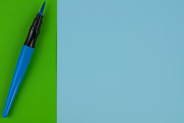 One blue color marker brush on green and blue paper sheets. Top view with copy space