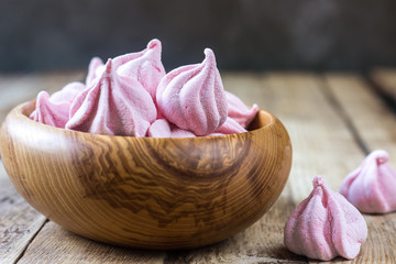 Fluffy white marshmallow in blue round bowl on old wooden table with copy space close up.