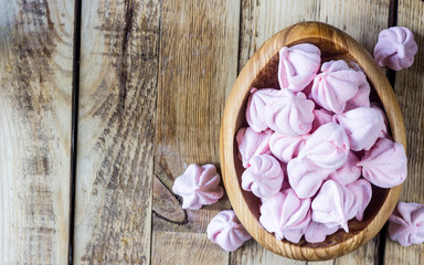 Fluffy white marshmallow in blue round bowl on old wooden table with copy space close up.