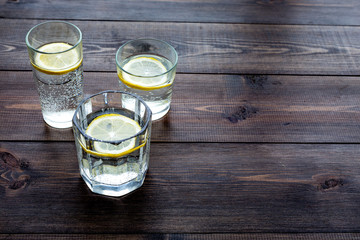 Refreshing drink. Water with lemon on dark wooden background top view copy space