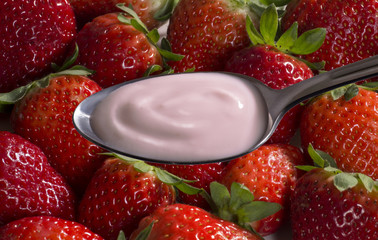 La cuchara con crema de yogurt de fresas y trozos.