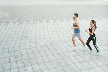 Young woman and man running in city copy space