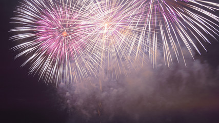 Pink and white sparks of festive fireworks in the dark sky