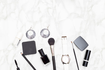 Female cosmetics and accessories are black and white on a marble background. Copy space