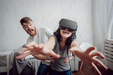 The young man with girlfriend playing games with virtual reality goggles