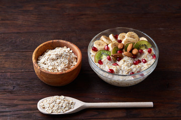 Diet breakfast oatmeal with fruits, bowl and spoon with oat flakes, selective focus, close-up