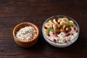 Diet breakfast oatmeal with fruits, bowl and spoon with oat flakes, selective focus, close-up