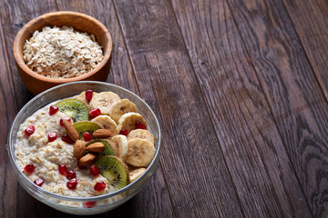 Diet breakfast oatmeal with fruits, bowl and spoon with oat flakes, selective focus, close-up