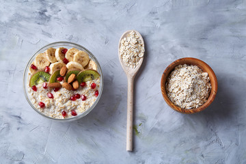 Diet breakfast oatmeal with fruits, bowl and spoon with oat flakes, selective focus, close-up