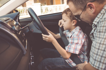 Happy father and son sitting in the car at the day time.