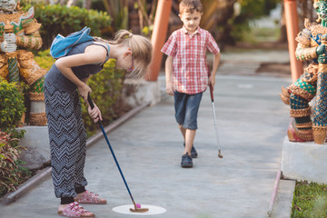 Happy brother and sister  playing mini golf.