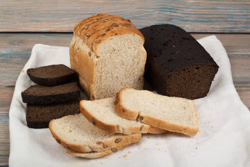 Many mixed breads and rolls of baked bread on wooden table background.