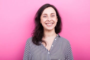 Fototapeta premium Portrait of happy woman laughing to the camera on pink background in studio