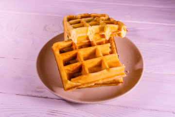 Ceramic plate with belgian waffles on wooden table