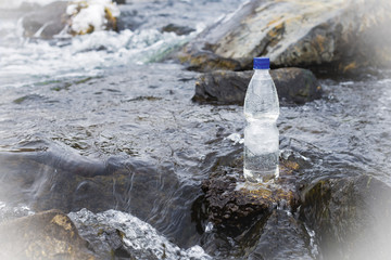 A bottle of clean water on rocks in a stream of water in a river