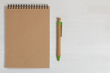 Pen of natural wood and a notebook on a white table.