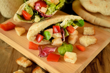 Caesar salad in pita bread on a wooden board