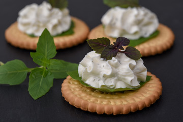 Bisquit cracker appetizers with cream cheese and basil topping