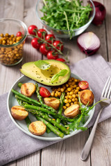 Healthy dinner with baked potatoes, green asparagus and spicy chickpeas, avocado, arugula, vegan, vegetarian food