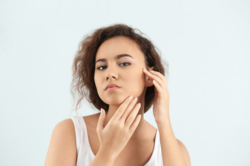 Beautiful young woman with acne problem on light background