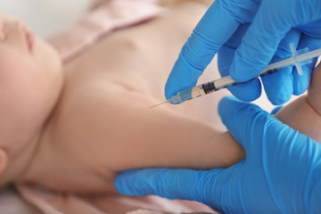 Doctor vaccinating baby in clinic, closeup