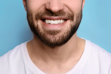 Obraz premium Young man with beautiful smile on grey background. Teeth whitening