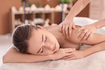 Obraz na płótnie Canvas Young woman enjoying massage in spa salon