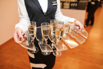 Waitress dressed in the uniform serving a set of champagne